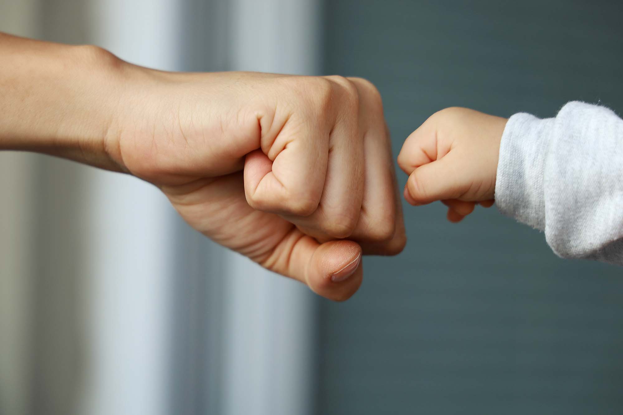 Fist Bump zwischen Erwachsenem und Kind. Vertrauensvolle Beziehung im Babysitting.