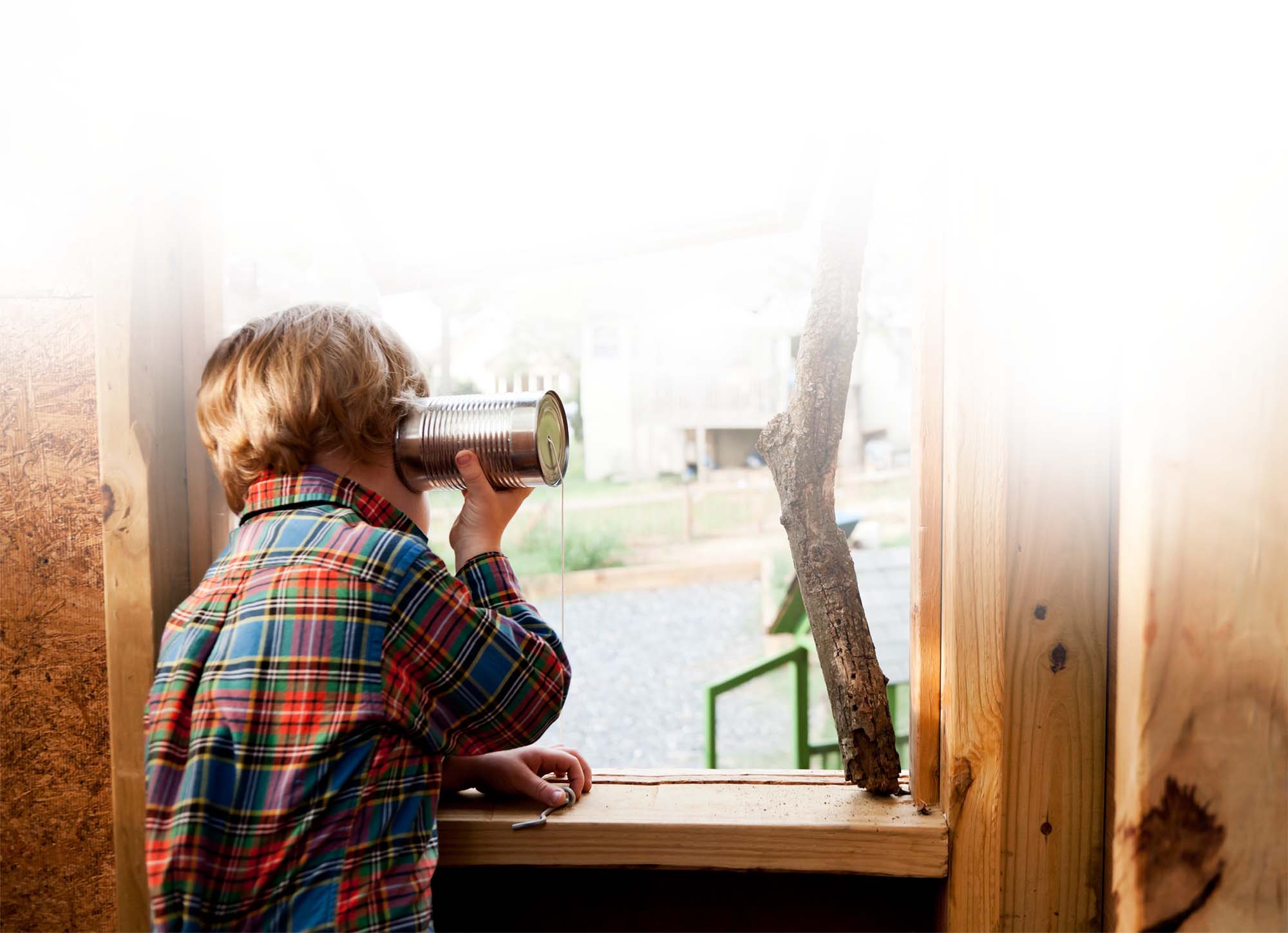 Kind telefoniert mit Blechdose. Spielerischer Kontakt und Verbindung.