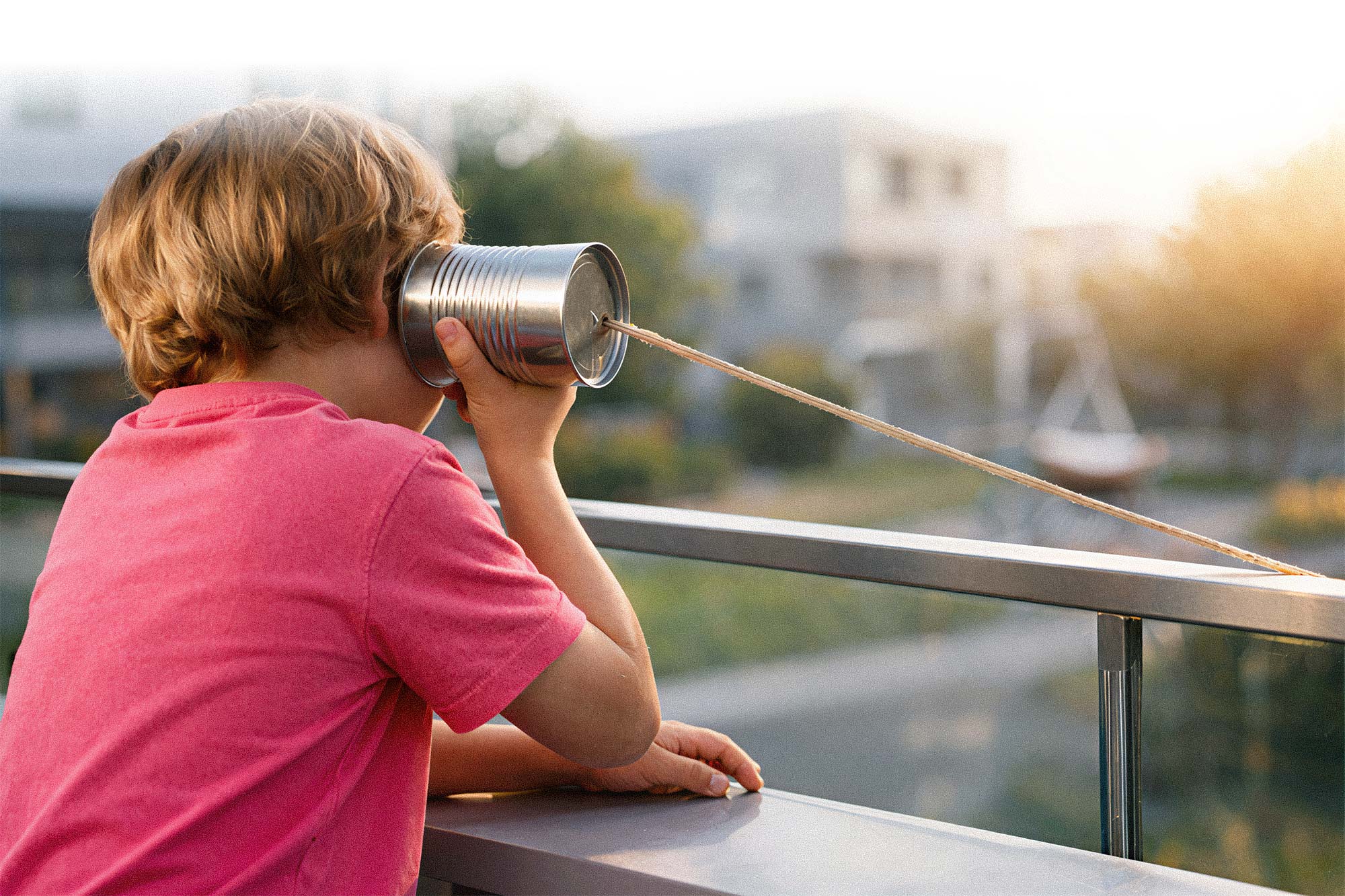 Kind telefoniert mit Blechdose. Spielerischer Kontakt und Verbindung.