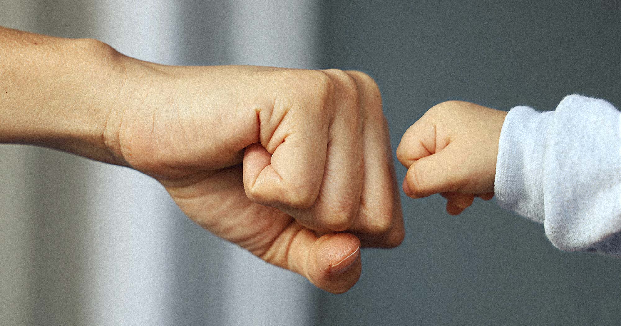 Fist Bump zwischen Erwachsenem und Kind. Vertrauensvolle Beziehung im Babysitting.