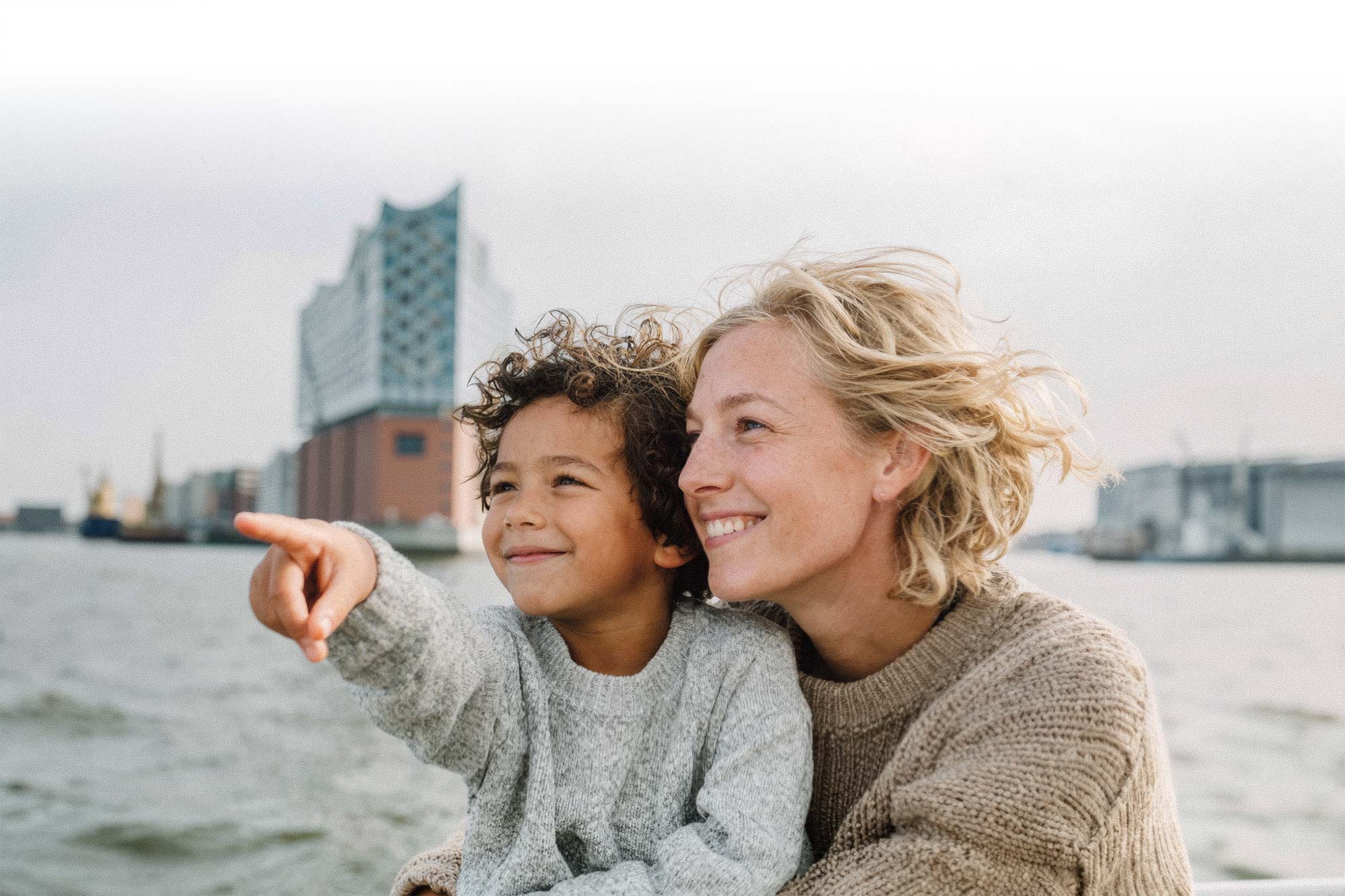 Babysitter sitzt mit Kind an der Alster in Hamburg. Persönliche Kinderbetreuung für Familien.