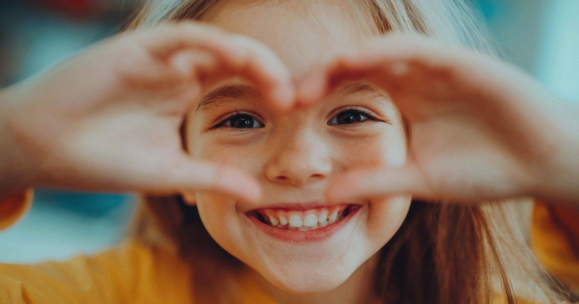 Kind formt Herz mit Händen. Vertrauensvolle Kinderbetreuung in ganz Deutschland.